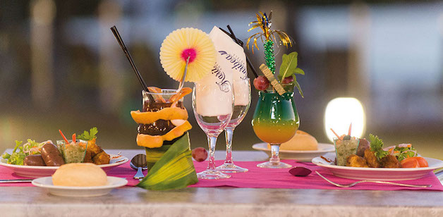 This is a picture of a table with two cocktails and two dinner plates set.